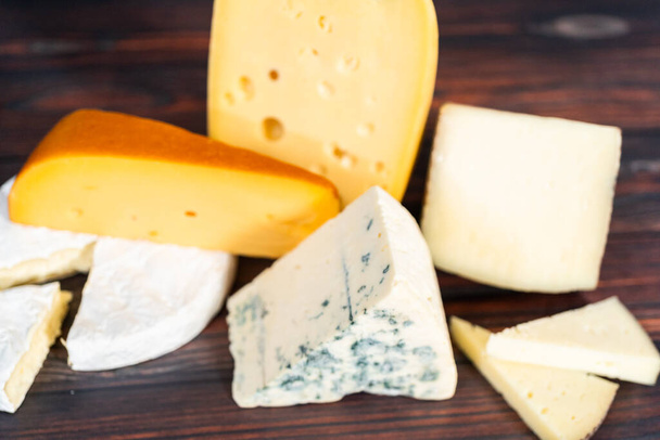 Varietà di grandi cunei di formaggio gourmet su uno sfondo di legno scuro. - Foto, immagini