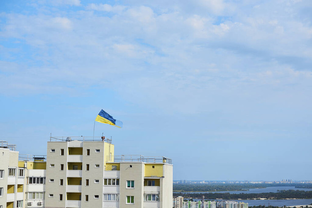 National blue and yellow flag of Ukraine waving on top of high apartment building for independence day celebration. Flag day. National symbols of country. - Фото, изображение