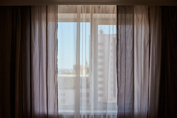 Fenêtres avec rideaux dans l'appartement de location. Vue du paysage urbain. Fenêtre lumineuse dans la chambre - Photo, image
