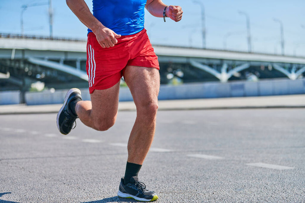 Un uomo in corsa. Uomo atletico che fa jogging in abbigliamento sportivo sulla strada cittadina. Stile di vita sano, sport fitness hobby. Allenamento in strada, sprint outdoor - Foto, immagini