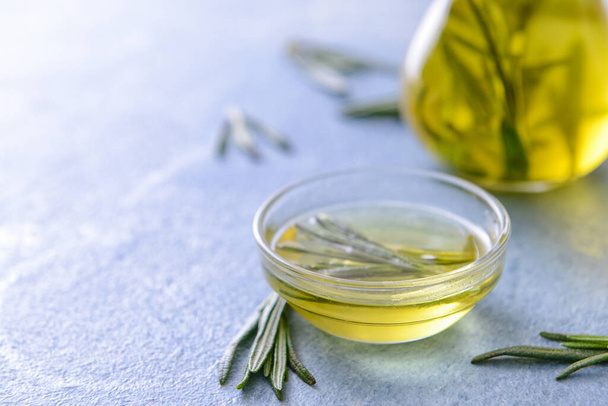 Bowl of rosemary oil on color background - 写真・画像