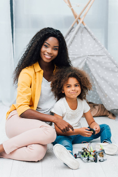Afrikai amerikai anya és gyermek ül a padlón közelében műanyag játékok  - Fotó, kép