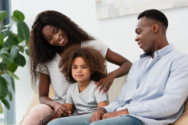 african american parents looking at curly daughter in living room  - Foto, Bild
