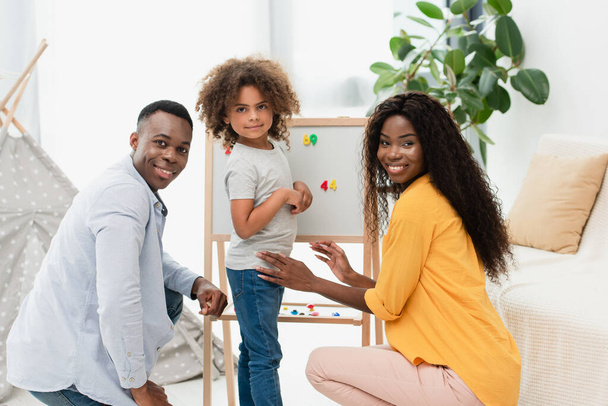afro-américaine famille regardant caméra près de chevalet magnétique  - Photo, image