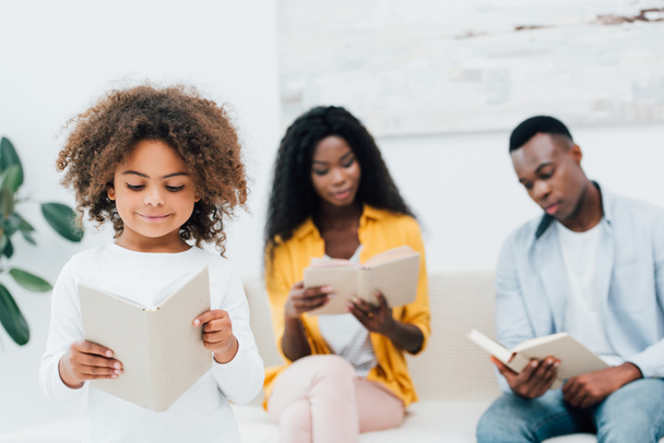 アフリカ系アメリカ人の子供が親の近くで本を読んで  - 写真・画像