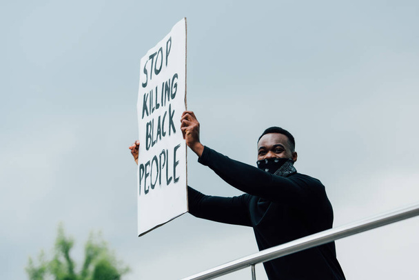 Αφροαμερικάνος που κρατάει πλακάτ και σταματάει να σκοτώνει μαύρους έξω.  - Φωτογραφία, εικόνα