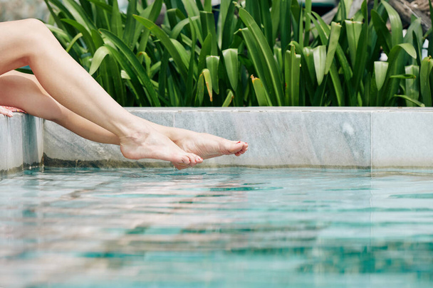 Schöne Beine einer jungen Frau beim Wasserspritzen im Schwimmbad - Foto, Bild