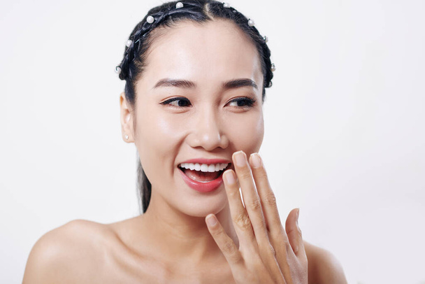 Glücklich schöne junge Asiatin lacht und bedeckt ihren Mund mit der Hand - Foto, Bild