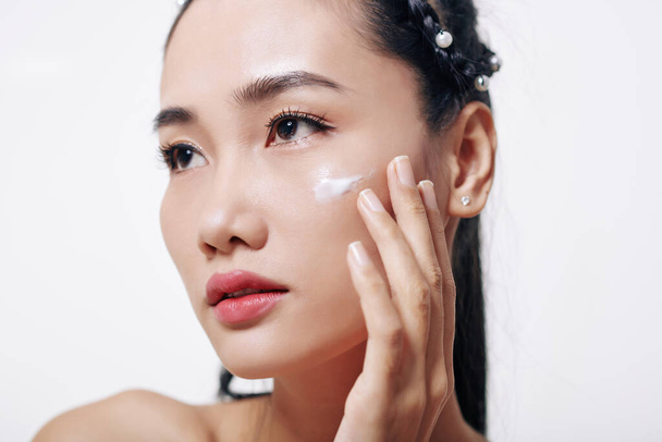 Krásné mladé vietnamky žena použití tání hydratační a omlazující krém na její tváři - Fotografie, Obrázek