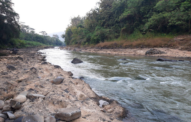 O rio com rochas ásperas ao lado dele e o rio tem uma longa curva com fundo de paisagem
 - Foto, Imagem