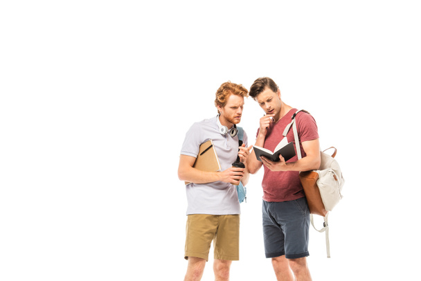 Estudiantes pensativos con taza desechable y mochilas mirando cuaderno aislado en blanco - Foto, Imagen