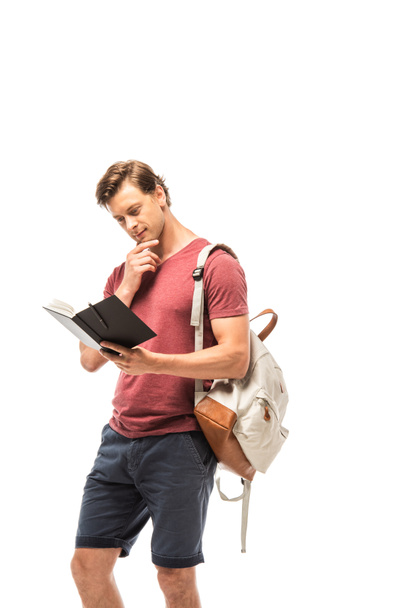 Pensive student with backpack looking at notebook isolated on white - Foto, Imagen