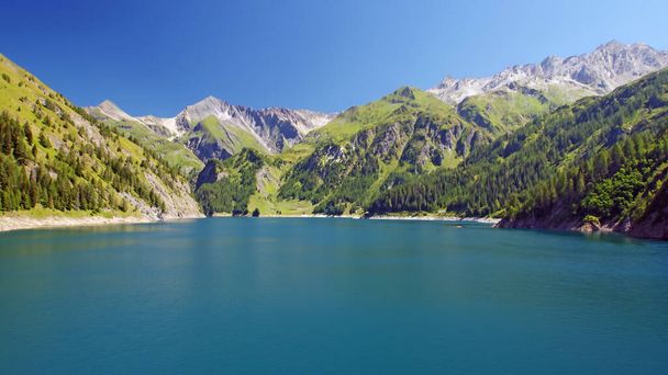 Sininen järvi, jota ympäröivät Sveitsin Alppien vuorenhuiput kauniina aurinkoisena kesäpäivänä. - Valokuva, kuva