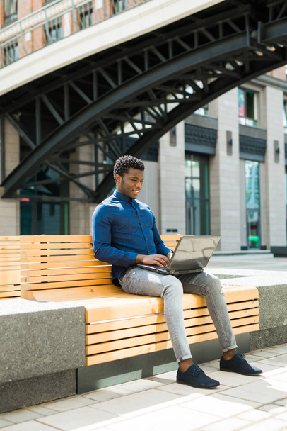 handsome young african man on bench with laptop - Foto, immagini