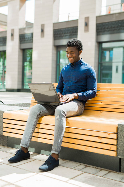 handsome young african man on bench with laptop - Foto, Imagen