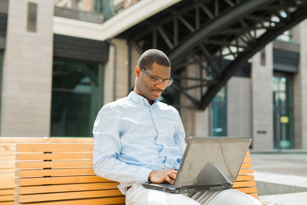 handsome young african man on bench with laptop - Foto, Imagem