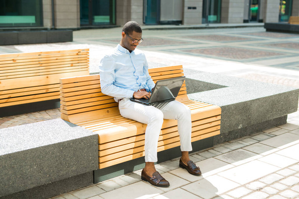 handsome young african man on bench with laptop - Fotoğraf, Görsel