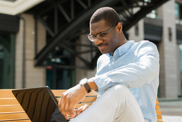 handsome young african man on bench with laptop - Foto, immagini