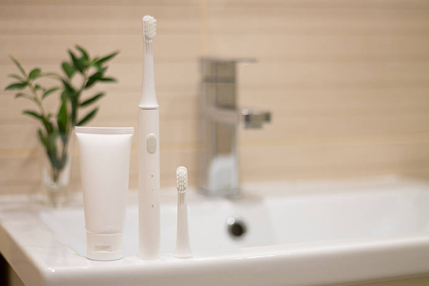 Brosse à dents électrique à ultrasons intelligente avec tête interchangeable et dentifrice dans la salle de bain à la maison. Hygiène buccodentaire, santé buccodentaire et souffle frais - Photo, image
