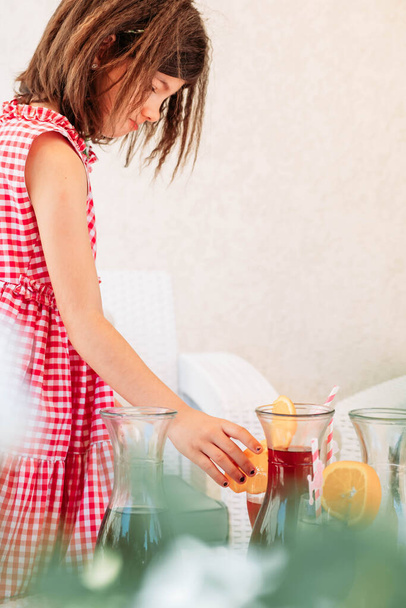 Little brunette girl choosing what juice to take from the table. Summer refreshment - Foto, Imagem