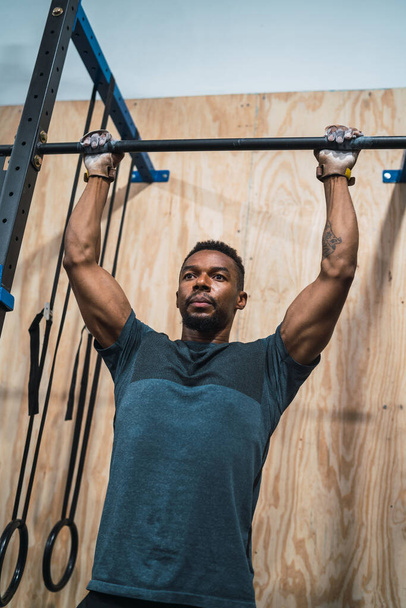 Portrait of an athletic man doing pull up exercise at the gym. Sport and healthy lifestyle concept. - Foto, afbeelding