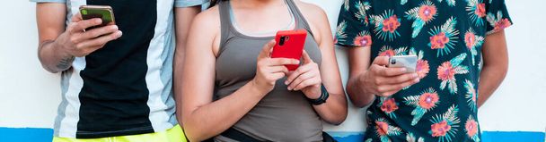 tre giovani che utilizzano il proprio smartphone in abiti estivi - Foto, immagini