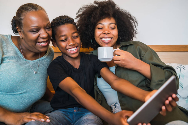 Portrait of African American grandmother, mother and son taking a selfie with digital tablet at home. Technology and lifestyle concept. - 写真・画像