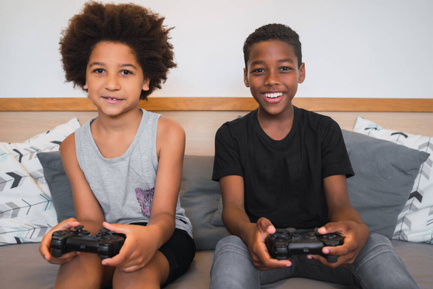 Portrait of two Afro American brothers playing video games at home. Lifestyle and technology concept. - Foto, afbeelding
