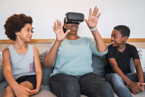 Portrait of African American grandmother and grandchildren playing together with VR glasses at home. Family and technology concept. - Foto, afbeelding