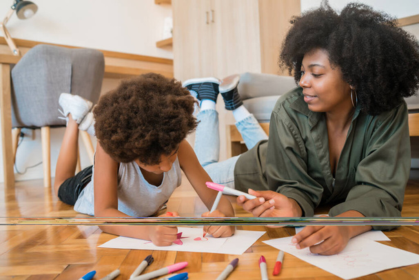 Portrait of young african american mother and son drawing with colored pencils on warm floor at home. Family concept. - Φωτογραφία, εικόνα