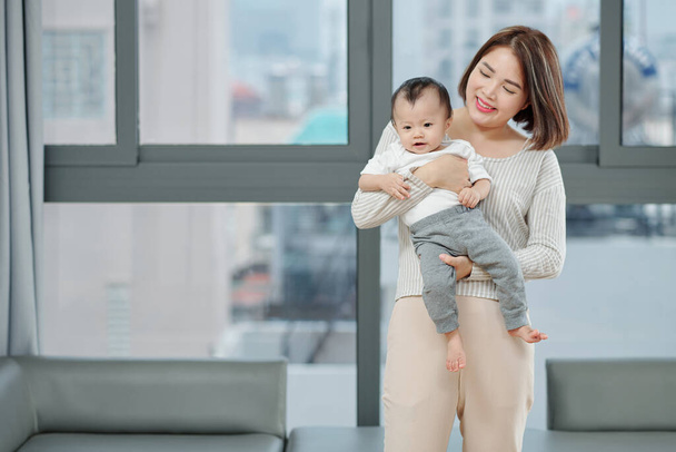 Uśmiechnięta młoda Azjatka niosąca swoją córeczkę - Zdjęcie, obraz