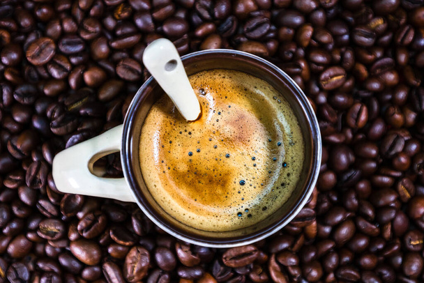 Kávový šálek s praženými kávovými zrny na červeném pozadí, koncept kávy, zblízka kávová fotka - Fotografie, Obrázek