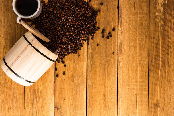 Kopje koffie, gebrande koffiebonen op houten ondergrond, houten vat bovenaanzicht, kopieerruimte voor tekst, close-up koffie foto - Foto, afbeelding
