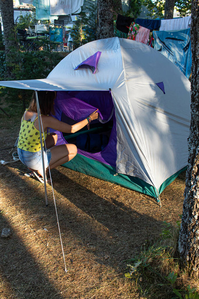 Attraente giovane femmina con una maschera che apre la zip dell'ingresso di una tenda - Foto, immagini