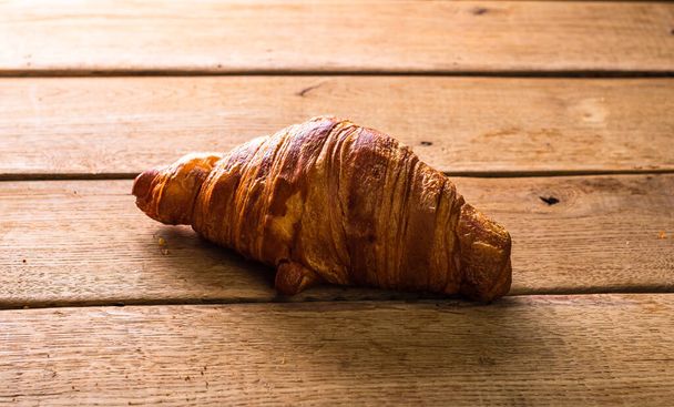 Detail of fresh croissant on wooden table. Food and breakfast concept. Top view and copy space - Photo, Image