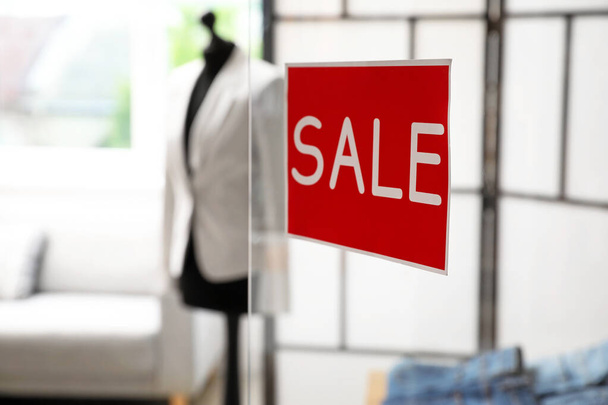 Sticker with word SALE on transparent door of modern clothes store - Фото, изображение