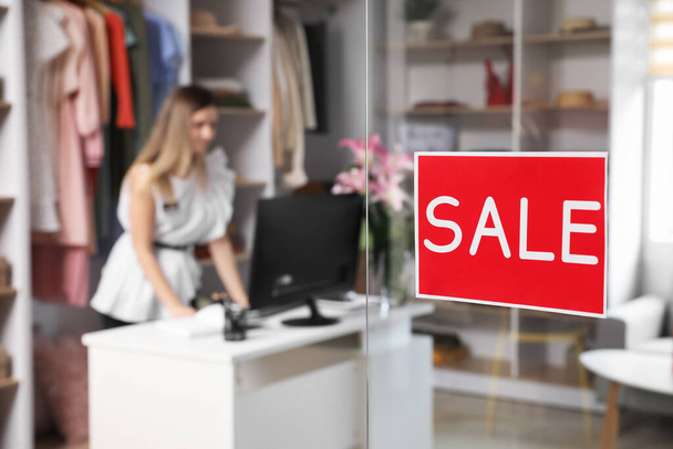 Sticker with word SALE on transparent door of modern clothes store - Photo, Image