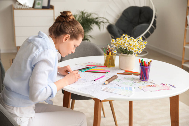 Young woman coloring picture at home - Photo, image