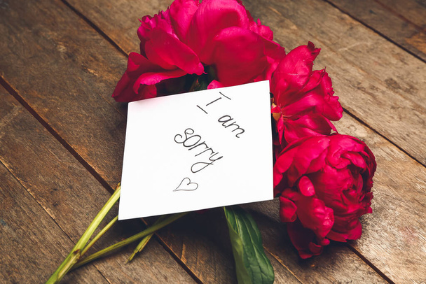 Kwiaty i kartka papieru z tekstem I AM SORRY na drewnianym tle - Zdjęcie, obraz