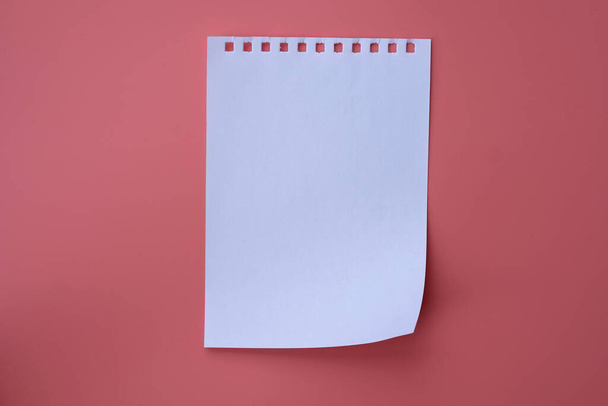 Fehér jegyzetfüzet rózsaszín háttérrel. Üres papír lap tetejére nézet. - Fotó, kép