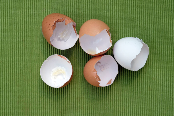 緑の背景に卵殻が茶色と白。鶏の卵殻. - 写真・画像