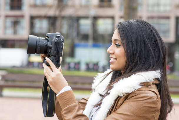 Mujer sonriente tomando fotos con cámara en la calle
. - Foto, imagen