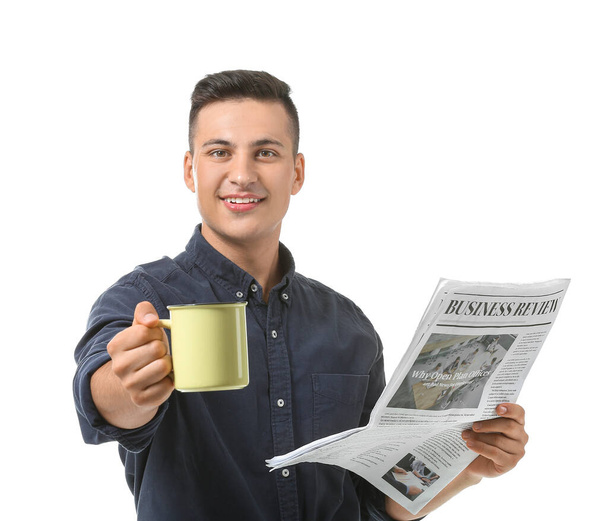 Handsome young man with cup of tea and newspaper on white background - Foto, immagini