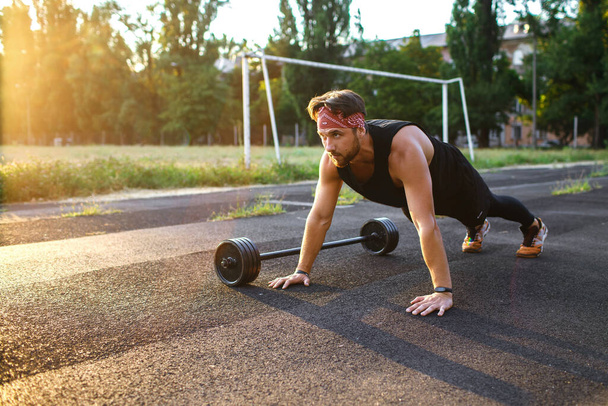 Male athlete doing push-ups outdoors, bodyweight athlete training, sports equipment and clothing, sunset, place for text, strong and handsome male body, burning extra calories - Photo, Image