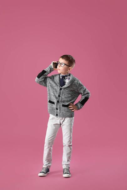 Cute little boy talking by phone on color background - Фото, изображение