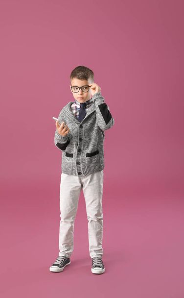 Cute little boy with mobile phone on color background - Photo, Image