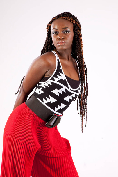 Mooie zwarte vrouw in rode broek op zoek bedachtzaam - Foto, afbeelding