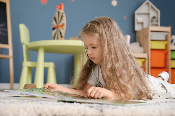 Aranyos kislány könyvet olvas otthon. - Fotó, kép