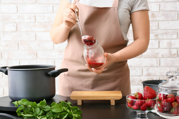 Femme faisant de la confiture de fraises sucrée dans la cuisine - Photo, image