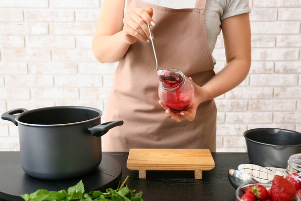 Woman making sweet strawberry jam in kitchen - Foto, Imagen